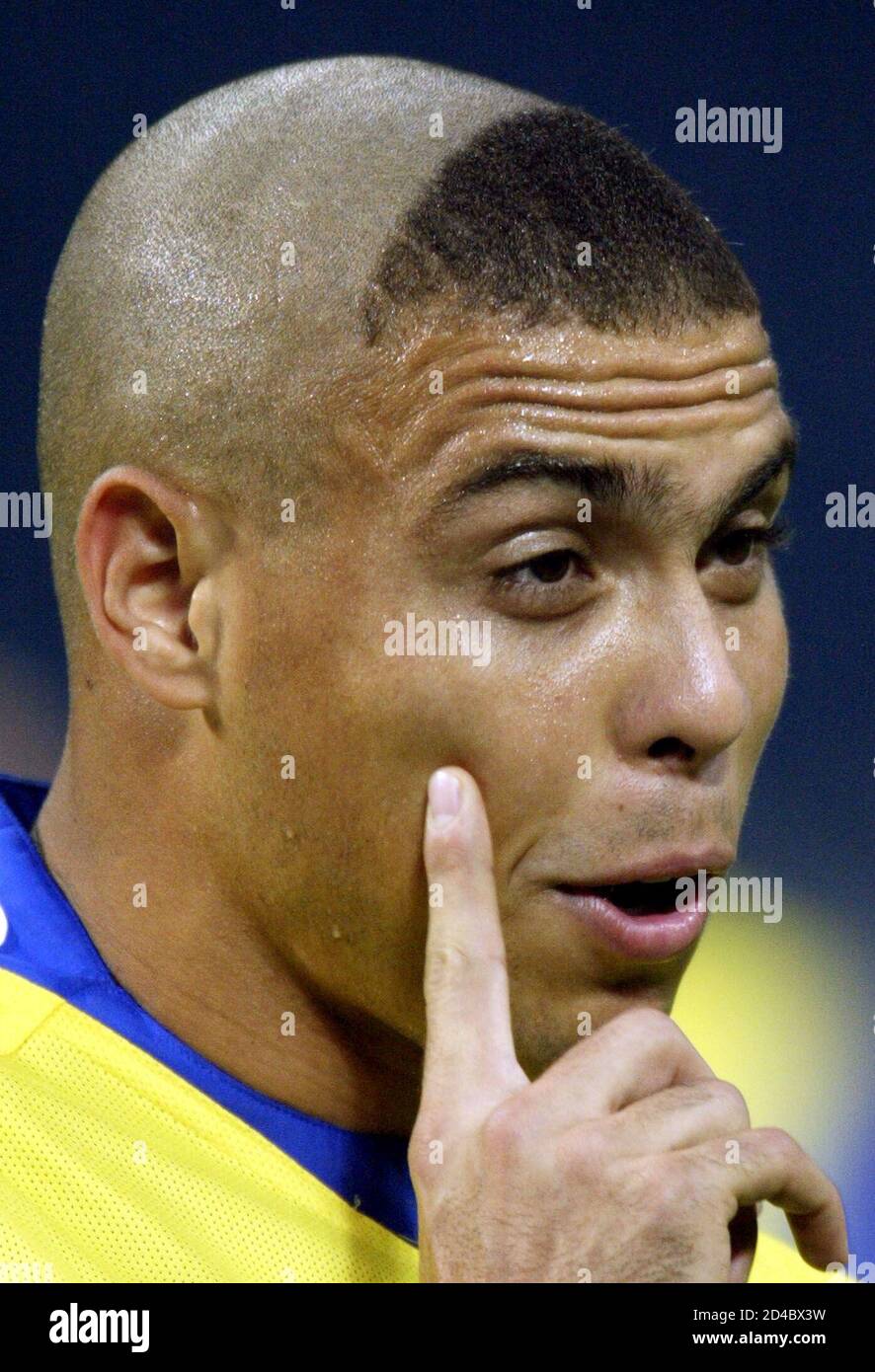 Brazil's striker Ronaldo points to his new hair cut as he trains with his  team at Saitama stadium June 24, 2002. Ronaldo, who has been suffering from  an injured thigh, took part