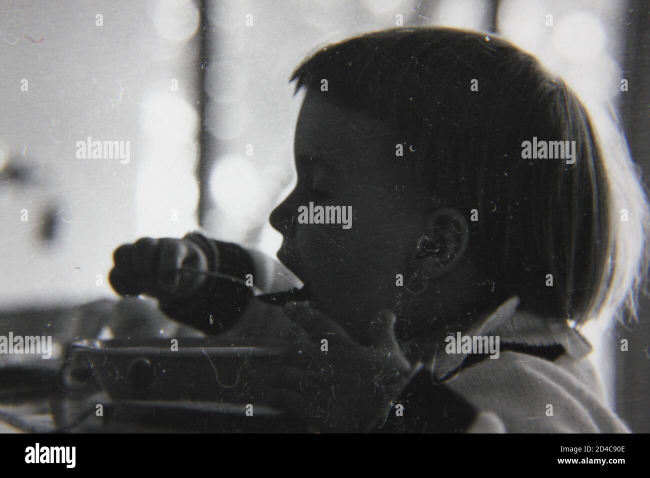 Fine 1970s vintage black and white photography of a little girl eating a bowl of soup for lunch. Stock Photo