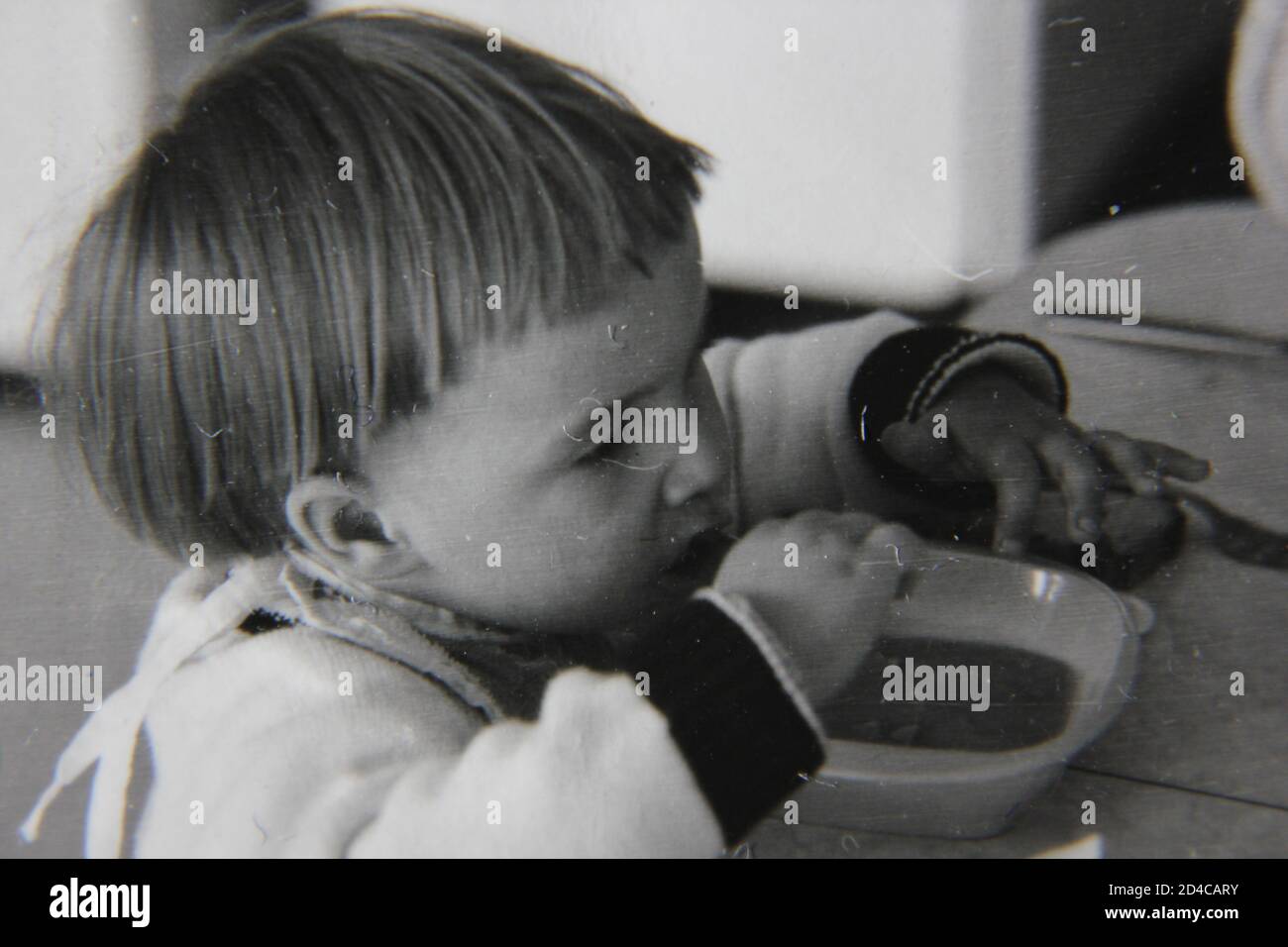 Fine 1970s vintage black and white photography of a little girl eating a bowl of soup for lunch. Stock Photo