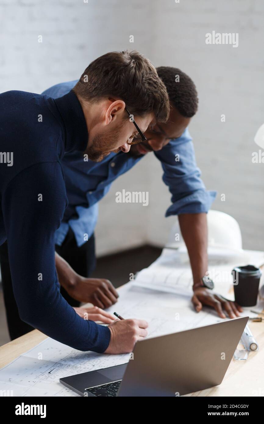 Multiracial engineer team working in office with blue prints and ...