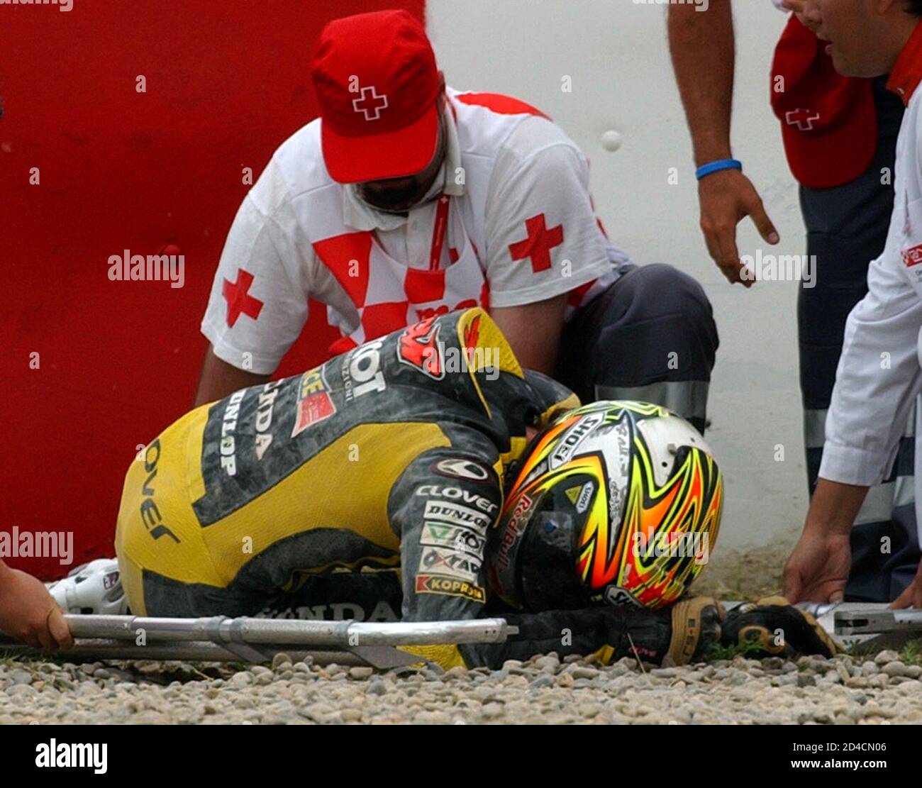 Italy's 250cc rider Dovizioso helped by medical staff after crash during free practice for Catalan Motorcycle Grand Prix. Italy's 250cc rider Andrea Dovizioso is helped by medical staff after a crash during free practice for the Catalan Motorcycle Grand Prix at Circuit de Catalunya race track near Barcelona June 11, 2005. Dovizioso came off the track on one of the Montmelo circuit's famously fast corners and slid across the gravel trap with his bike before thumping back-first into the tyre wall. REUTERS/Albert Gea Stock Photo
