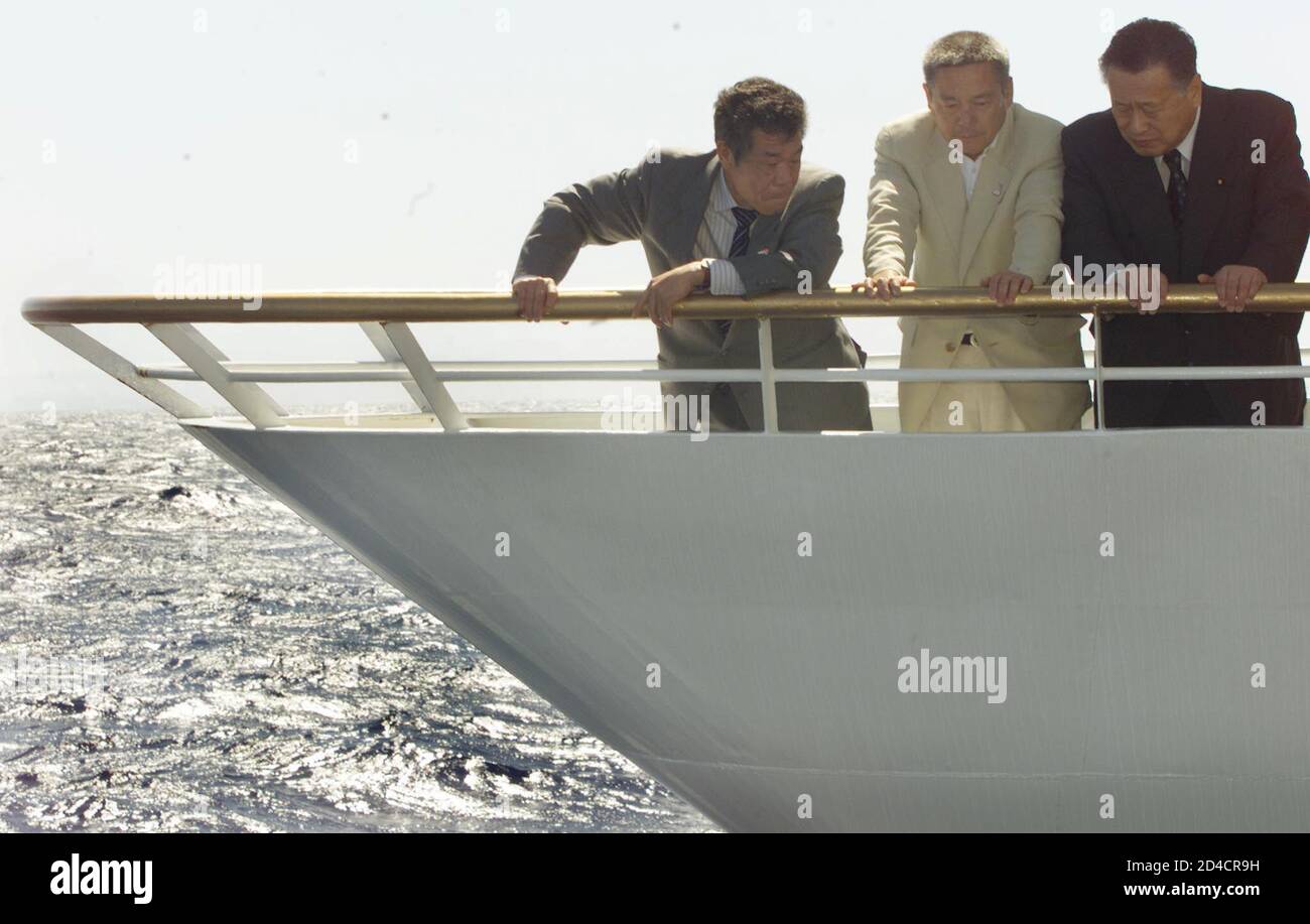 Japanese Prime Minister Yoshiro Mori (R), Mitsunori Nomoto (L) and Kazuo Nakata (C) peer overboard into the ocean on March 20, 2001 where the Ehime Maru sank nine miles South of Honolulu after the submarine USS Greeneville collided with and sank the Japanese ship on February 9. Nine members of the ship were never found. Mori and the families were taken aboard a commercial ship for a three hour roundtrip from Honolulu harbor to the offshore site to pay their respects to the missing crewmen. REUTERS/Anthony P.  APB Stock Photo