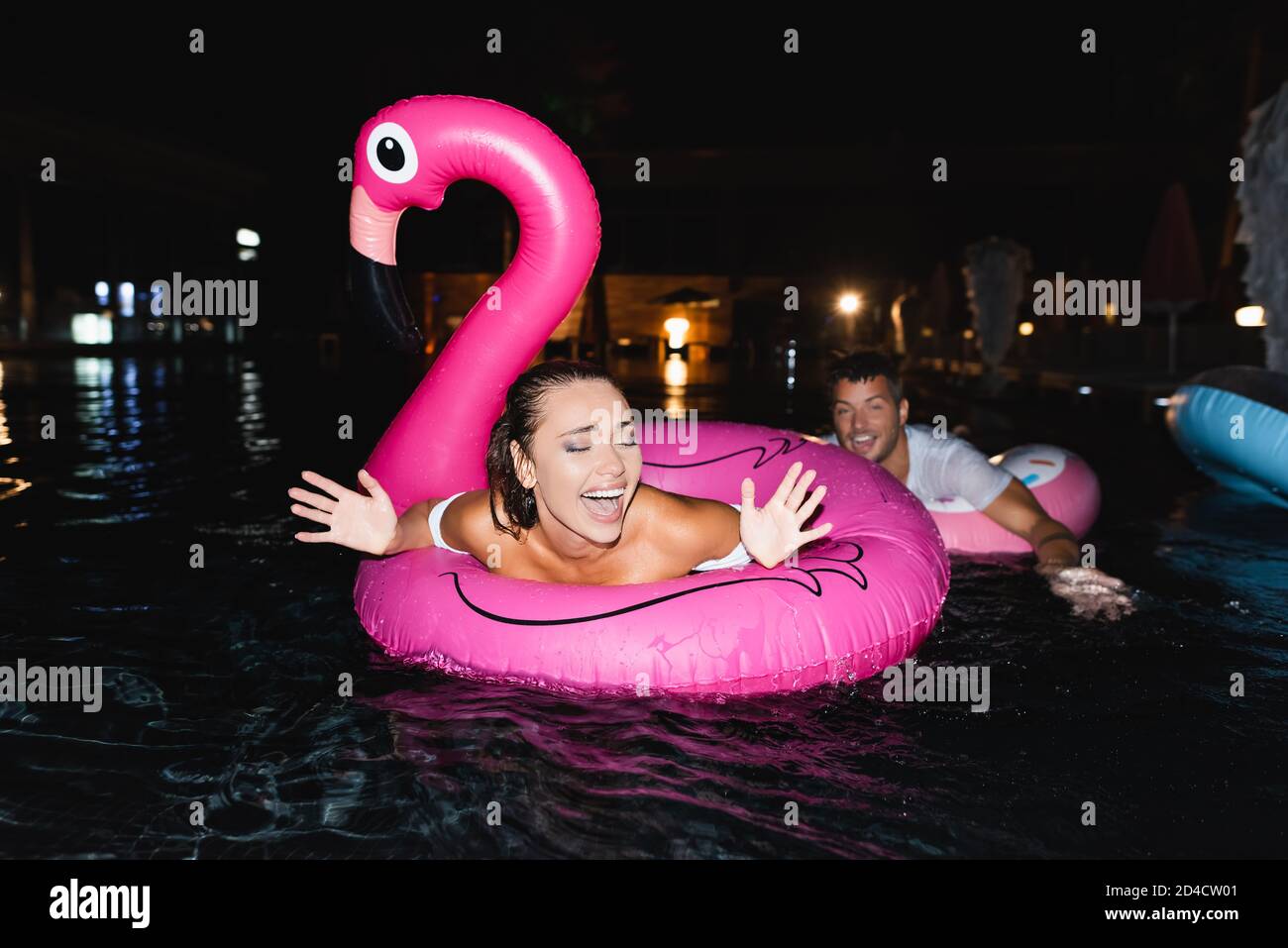Selective focus of excited woman swimming in ring in pool near ...