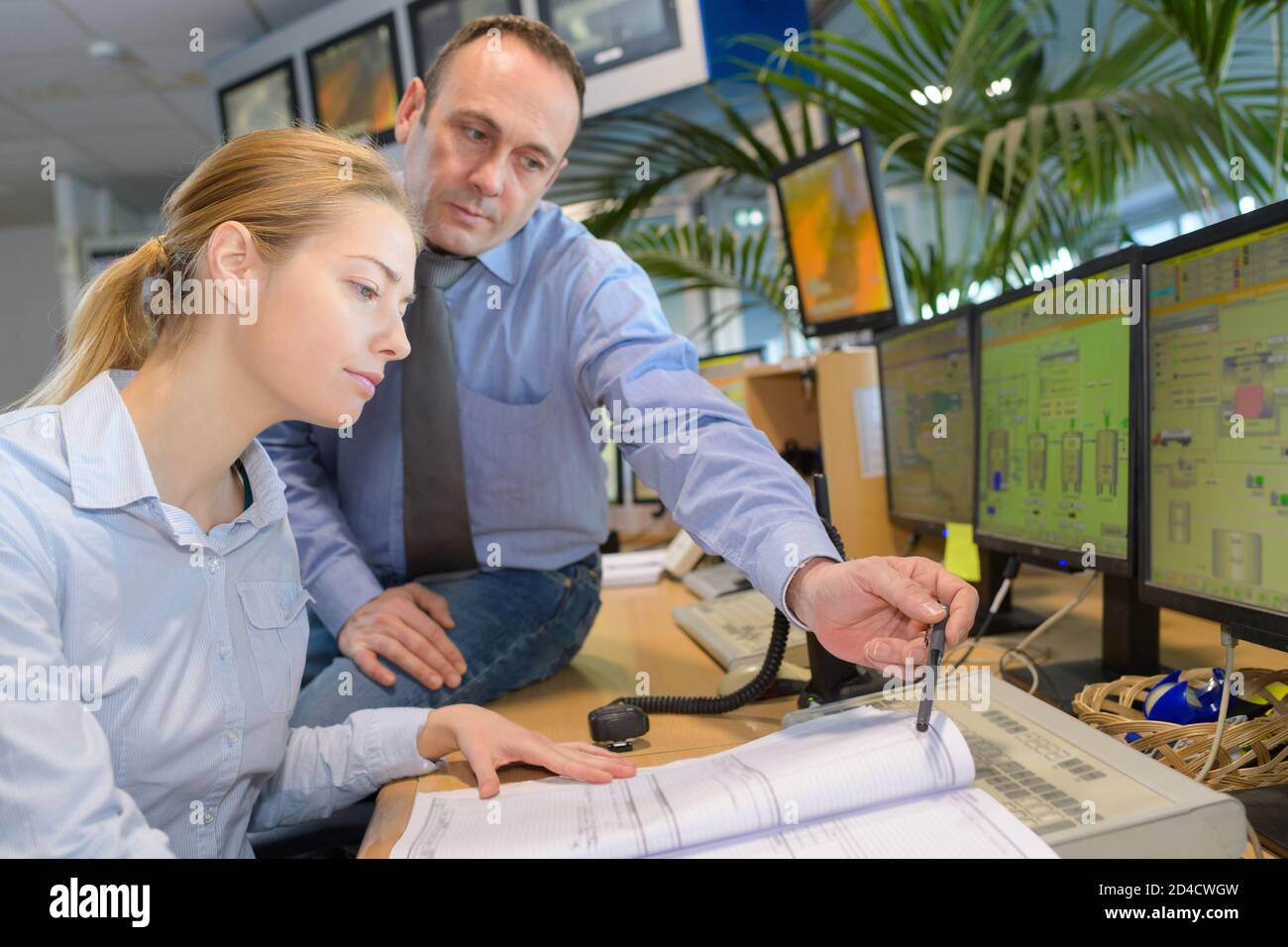 workers looking at paperwork in computer control center Stock Photo - Alamy