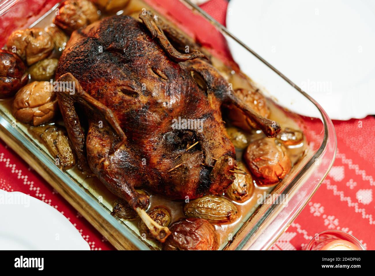 A closeup of a crispy baked goose in its own fat with potatoes and