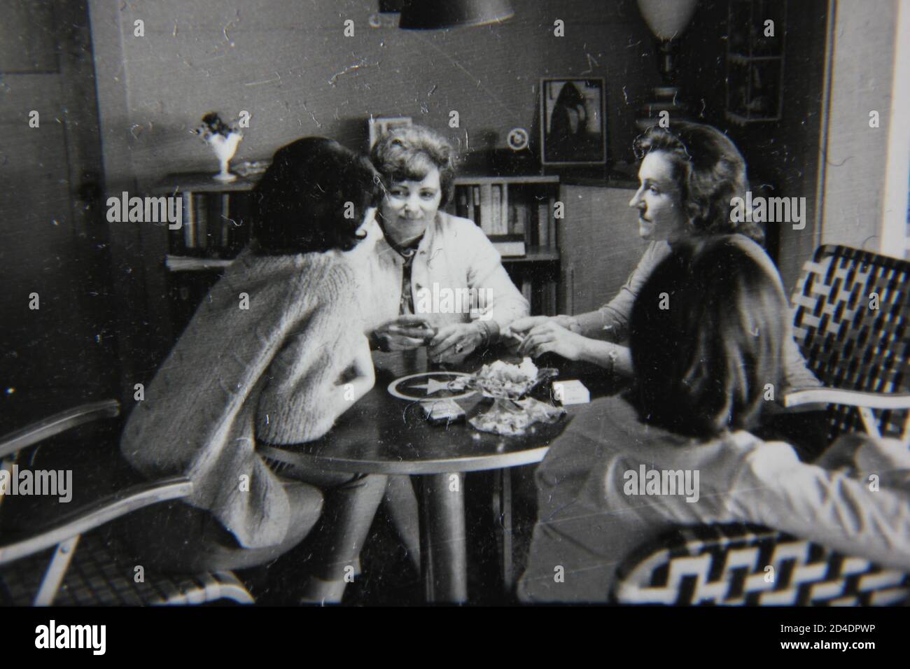 Fine 1970s vintage black and white photography of a casual gathering of girl friends in the kitchen for a cup of coffee. Stock Photo