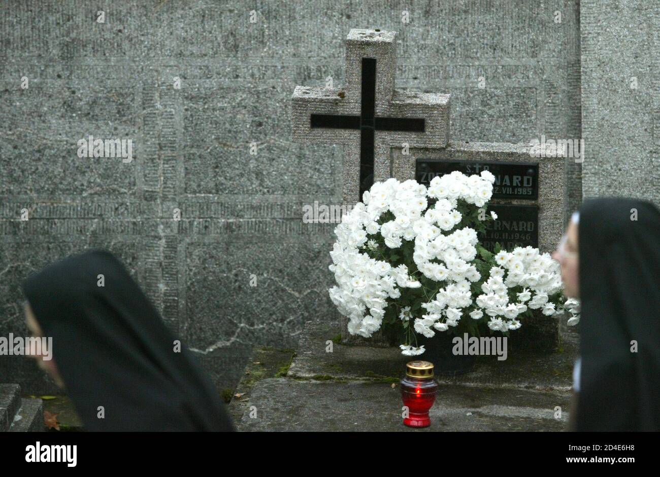 Two Polish nuns pass a grave at the Krzyz cemetery on All Saints Day in Tarnow, southern Poland November 1, 2004. Thousands of people gathered at cemeteries to celebrate the religious holiday. REUTERS/Katarina Stoltz  KS/WS Stock Photo