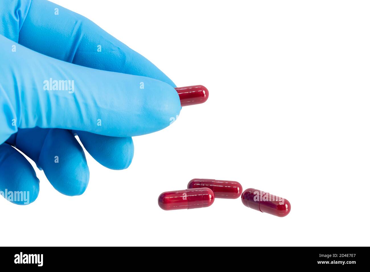 Hand with blue latex glove holds a capsule of metamizole, is a painkiller, spasm reliever, and fever reliever that also has anti-inflammatory effects. Stock Photo