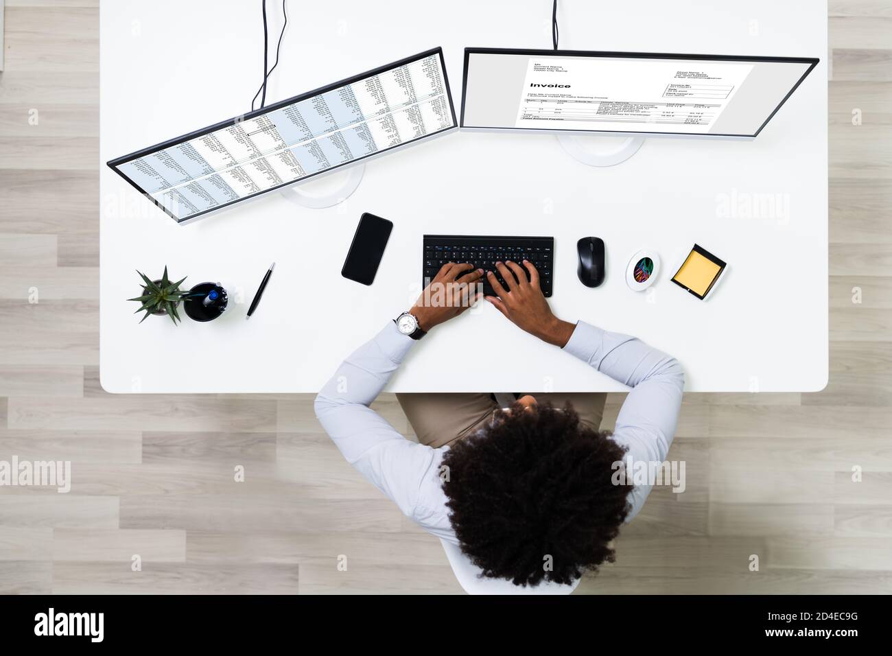 Looking At Invoice And Spreadsheet On Computer At Work Stock Photo