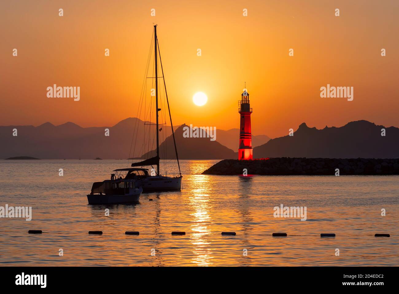 Lighthouse at sunset in harbour Stock Photo