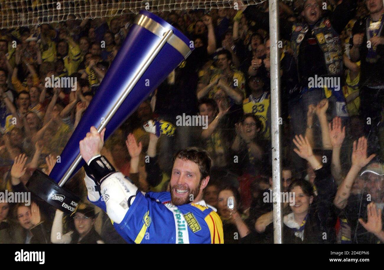 NHL player Joe Thornton holds up the trophy after winning the Swiss ice hockey championships with HC Davos.  NHL player Joe Thornton of the Boston Bruins, playing for Swiss club HC Davos during the NHL lockout, holds up the trophy after winning the Swiss ice hockey championships in Davos April 7, 2005. Davos beat the ZSC Lions of Zurich in their fifth game of the playoff finals 3-2 to secure Davos' 27th championship title. REUTERS/Sebastian Derungs Stock Photo