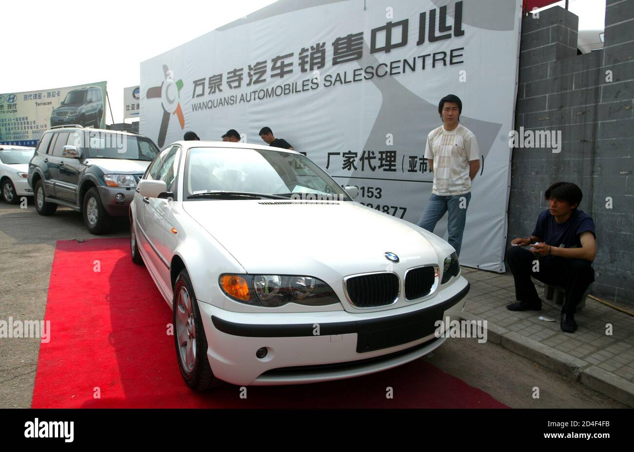 Chinese Salespeople Wait For Customers Next To A New China Made Bmw 318i At An Outdoor Auto Market In Beijing April 19 2004 The China Made Bmw 318i Made Its Debut With A Price