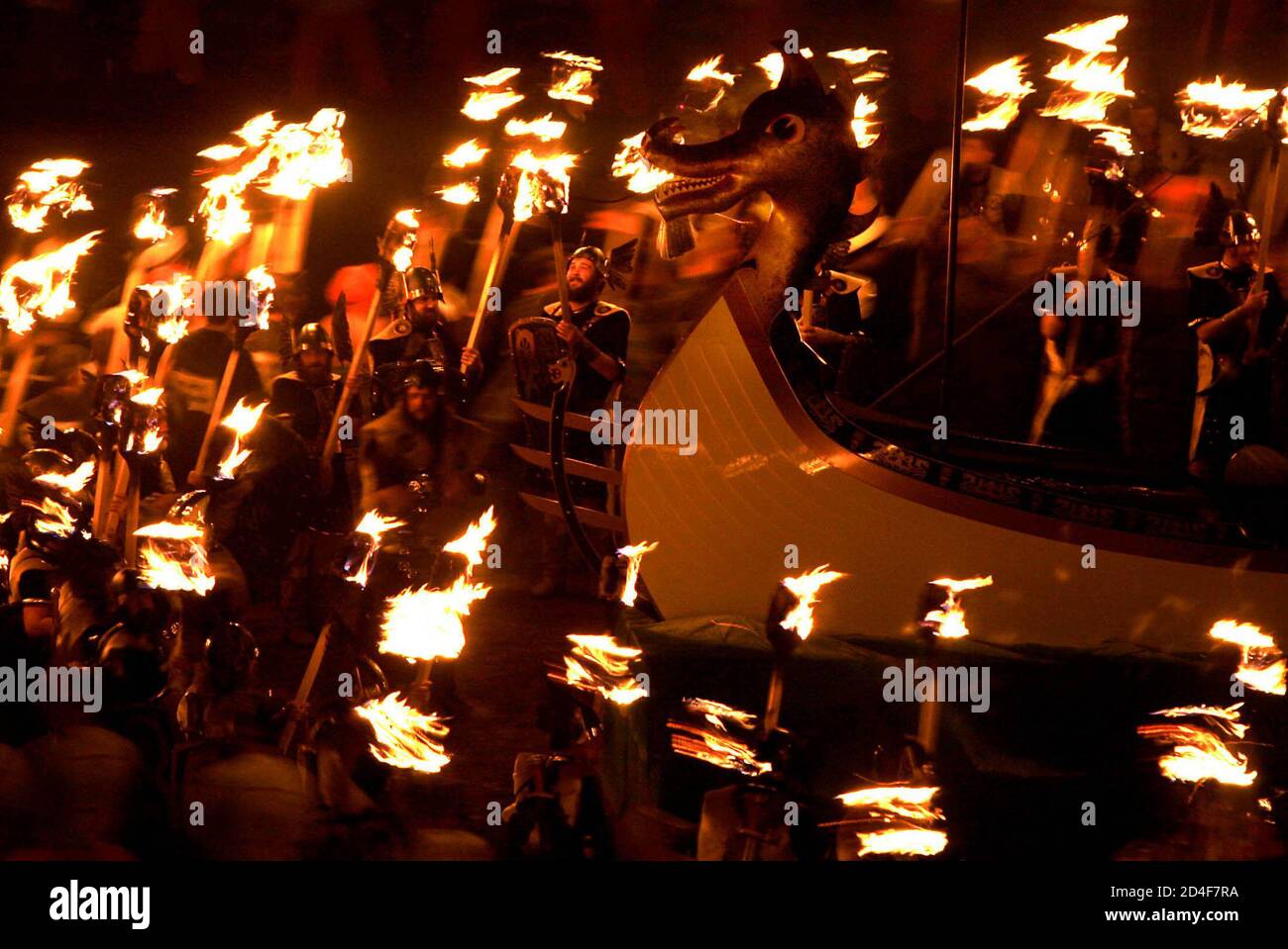 Locals dressed in costume throw burning torches as they surround a replica Viking galley in Lerwick during the Up Helly Aa Festival on the Island of Shetland in Scotland January 25, 2005. The Up Helly Aa Festival, introduced by men returning from the Napoleonic Wars of the early 19th century, takes place annually on the lastTuesday of January. Participants drag the replica Viking galley through the streets of Lerwick to a designated point where it is ceremonially burnt. REUTERS/Jeff J Mitchell  JJM Stock Photo