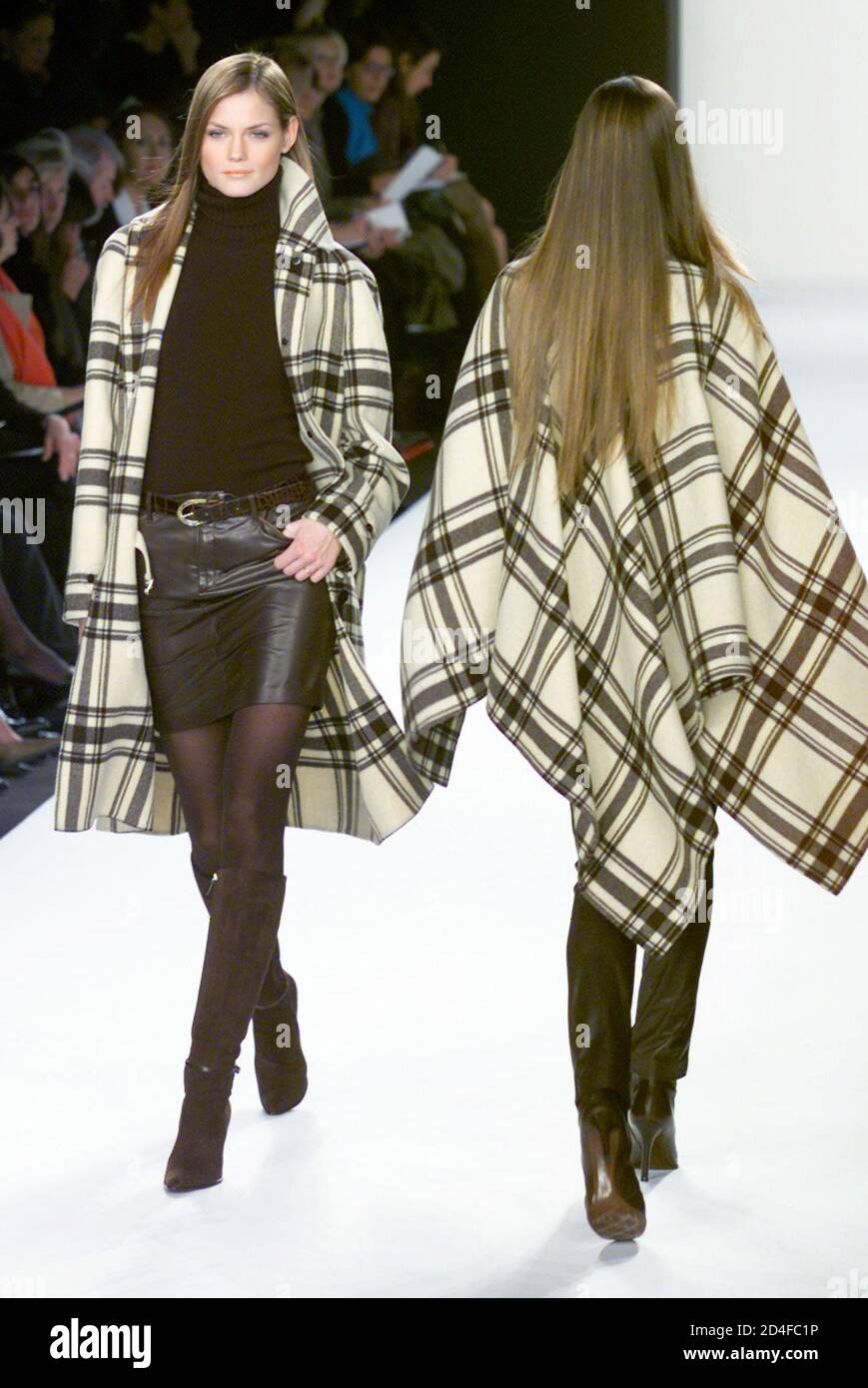 A model for designer Ralph Lauren wears a cream/brown double face cashmere  blend blanket plaid coat with ebony cashmere turtleneck and espresso  leather skirt (L) as she passes another model wearing a
