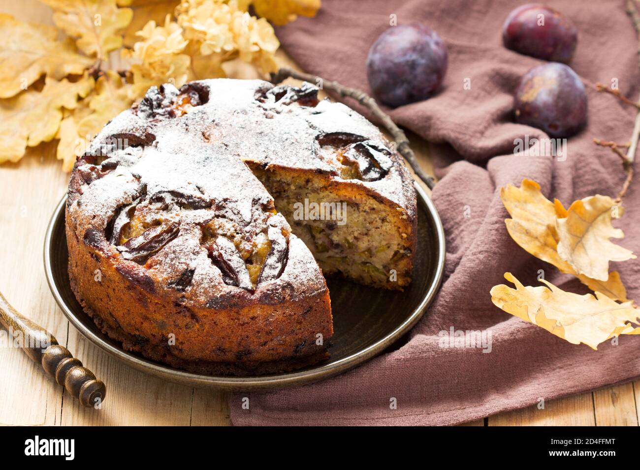 Plum pie with nuts and chocolate on a wooden background. Rustic style. Stock Photo