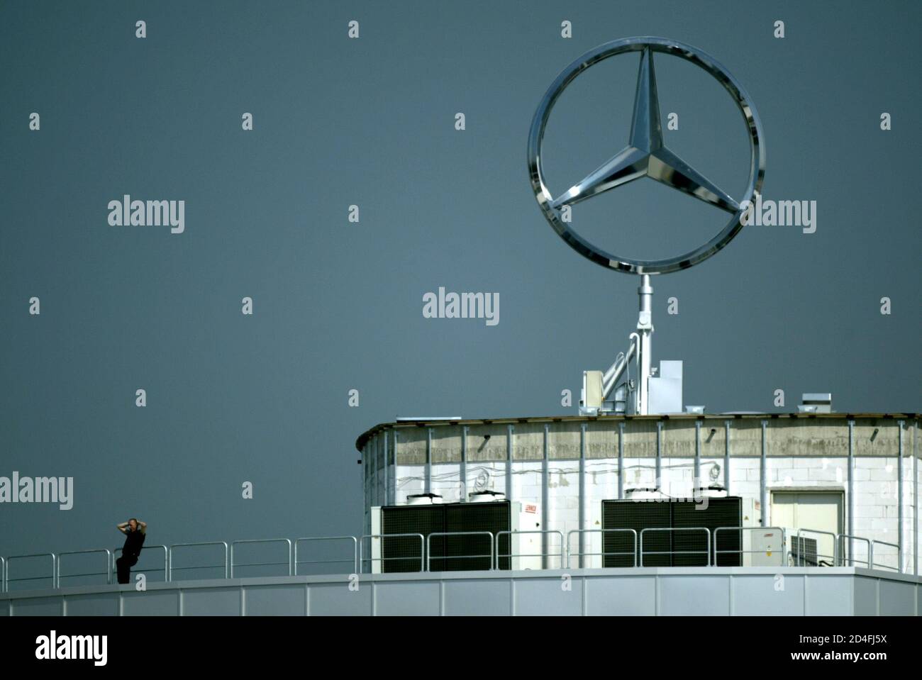A SPECTATOR SITS UNDER A MERCEDES SYMBOL AS HE WATCHES PRACTICE FOR THE GERMAN GRAND PRIX AT HOCKENHEIM CIRCUIT DURING PRACTICE FOR THE GERMAN GRAND PRIX. Stock Photo
