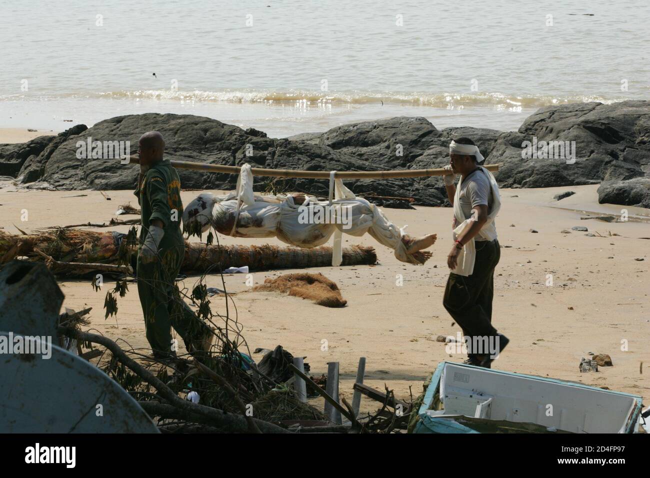 Rescue workers carry a body of a victim from Sunday's tsunami at Khao Lak  beach, about 900 km (560 miles) south of Bangkok December 28, 2004.  Searchers have retrieved 770 bodies, both