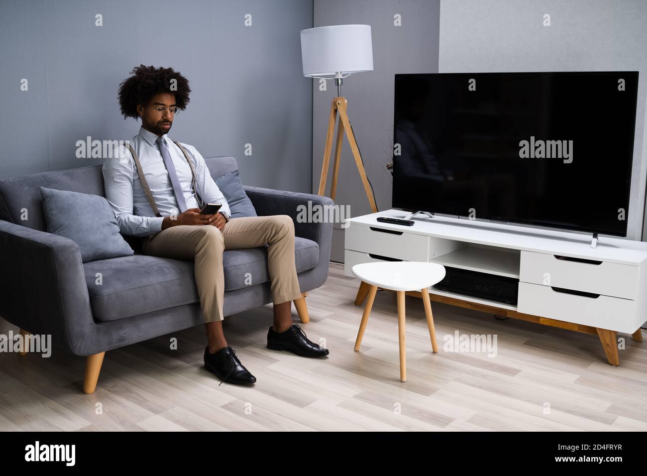Young Man Sitting On Couch Using Smartphone At Home Stock Photo
