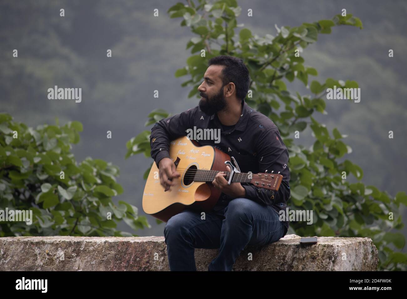 Dehradun, Uttarakhand/India-September 12 2020:A youngster playing guitar in beautiful hills. Stock Photo