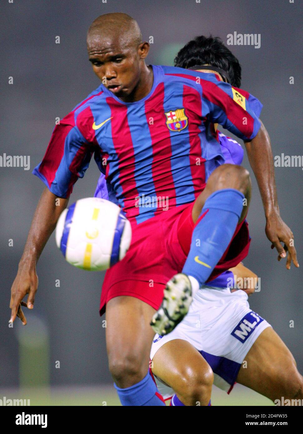 Spanish Club Barcelona S Samuel Eto O Controls The Ball In Front Of Japan S J League Club Yokohama Marinos Naoki Matsuda During The First Half Of An Exhibition Match Of Barcelona S Asian Tour At Nissan