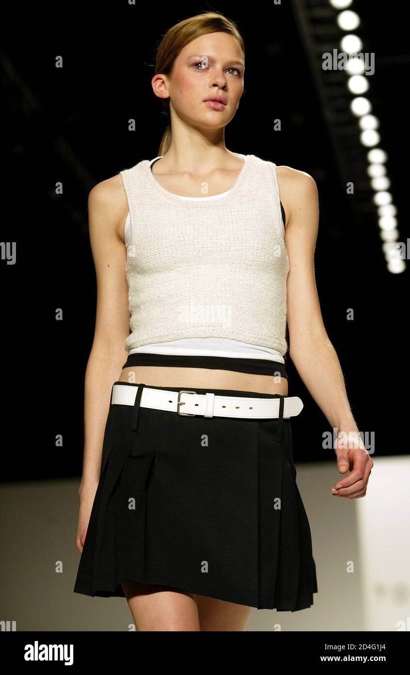 A model for designer Tommy Hilfiger walks the runway wearing a silver lurex  angora tank, white nylon tank and black nylon tank with a navy gabardine  pleated skirt during the presentation of