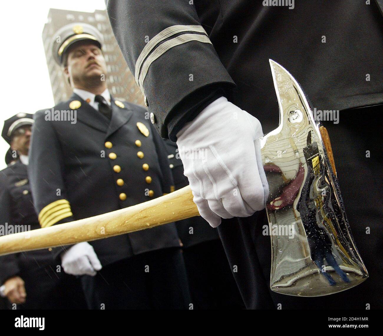 A firefighter carries an axe during the FDNY Memorial Day event in New York, October 12, 2002. Firefighters from across the world filled Madison Square Garden and the surrounding blocks on Saturday to honor the 343 firefighters who died in the World Trade Center hijack attack last year. [Because last year's event was canceled due to the attack on the trade center, this year, an honor guard carried 356 flags, to also honor those firefighters who died in the line of duty in New York since mid-October 2000.] Stock Photo