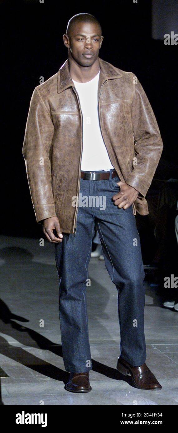 A model wears an aged brown leather jacket, white cotton t-shirt, ink blue  denim pants, and brown point toe loafers at designer Kenneth Cole's Fall  2001 presentation in New York on February