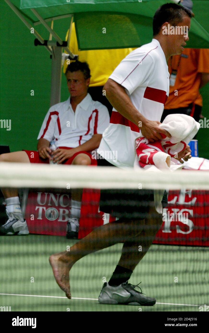 AUSTRALIA'S LLEYTON HEWITT SITS IN CHAIR AS CECIL MAMIIT FROM THE U.S.  HOBBLES PAST AT THE AUSTRALIAN OPEN IN MELBOURNE. Australia's Lleyton  Hewitt (L) sits in his chair as Cecil Mamiit from