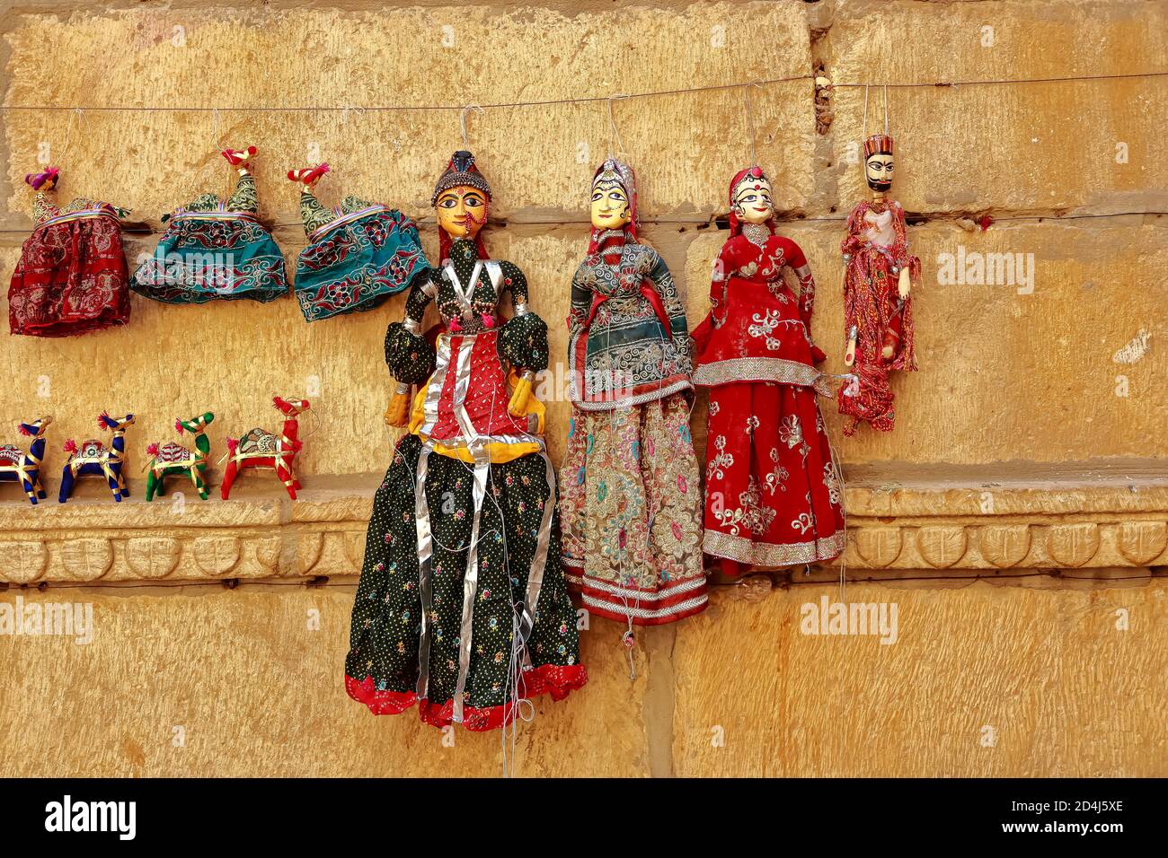 Colorful human shaped Puppets wearing colorful clothes hanging against the wall in Rajasthan India on 21 February 2018 Stock Photo