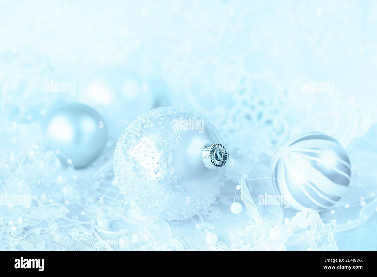 Beautiful Christmas decoration in white and blue colors: several Christmas balls with white ribbon and pearls on a pink lacy background, with space fo Stock Photo