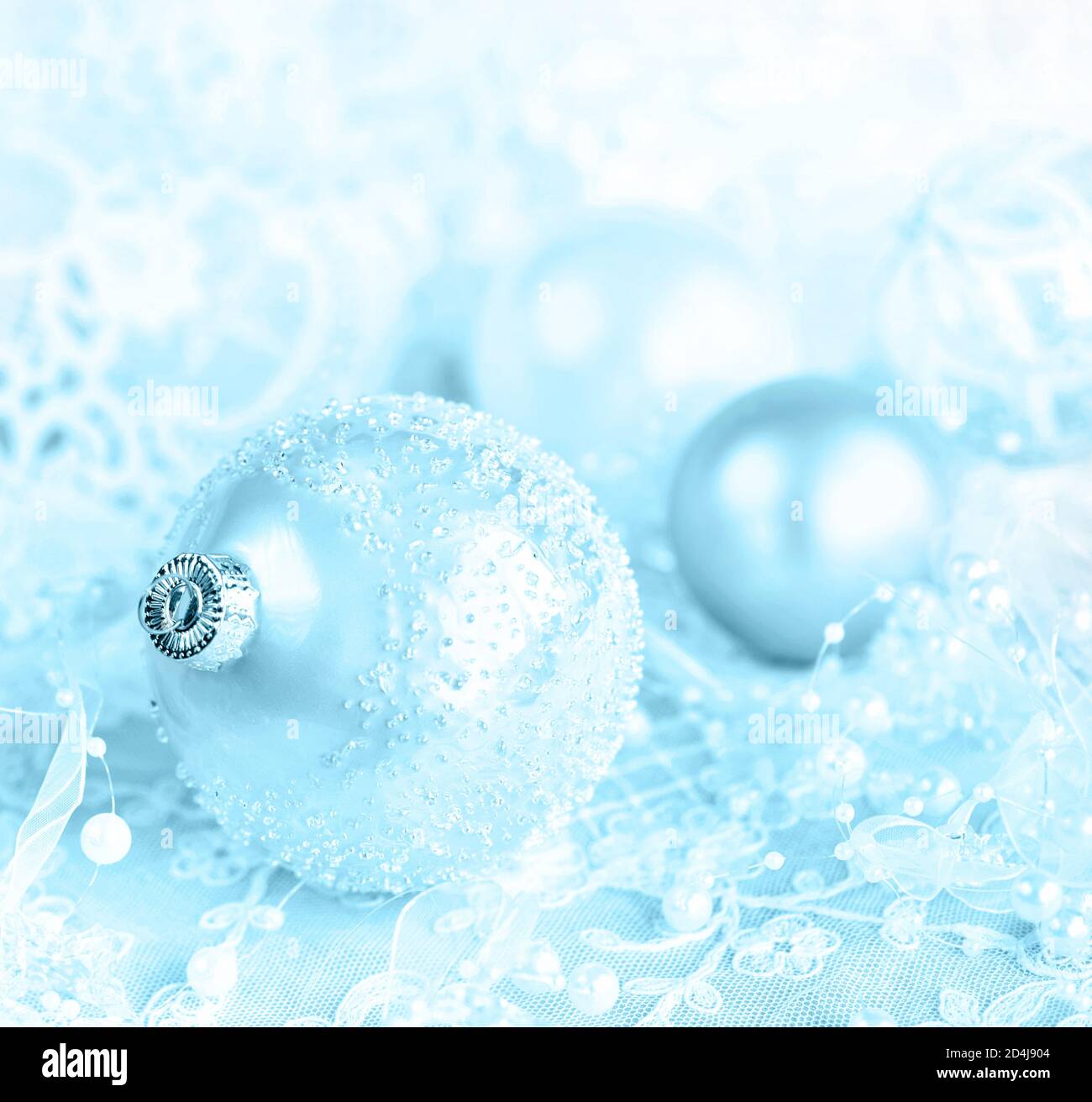 Beautiful Christmas decoration in white and blue colors: several Christmas balls with white ribbon and pearls on a pink lacy background, with space fo Stock Photo