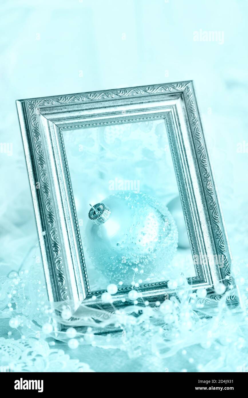 Beautiful Christmas decoration: large blue Christmas ball with a white ribbon and pearls in a silver vintage frame on a light background, with space f Stock Photo