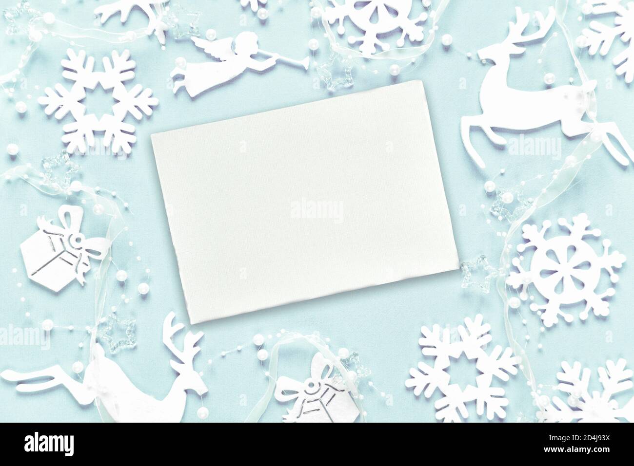 Christmas greeting card composed of white christmas decoration: snowflakes, deers, flying angel and gift boxes on blue background. Flat lay compositio Stock Photo