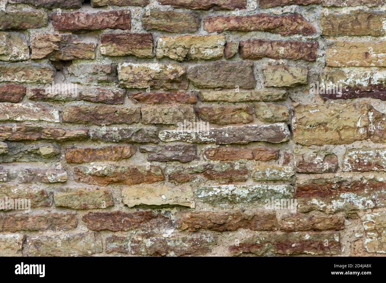 The surface of an old stone wall, masonry of uneven wild hewn stones. Stock Photo