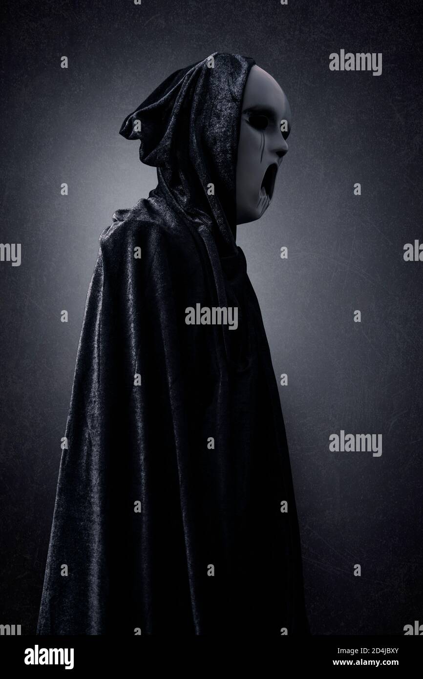 Ghostly figure in hooded cloak in the dark Stock Photo - Alamy