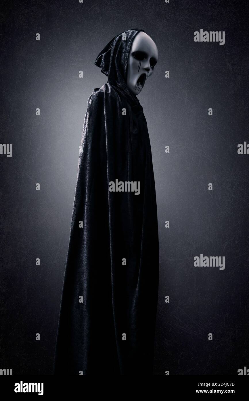 Ghostly figure in hooded cloak in the dark Stock Photo - Alamy