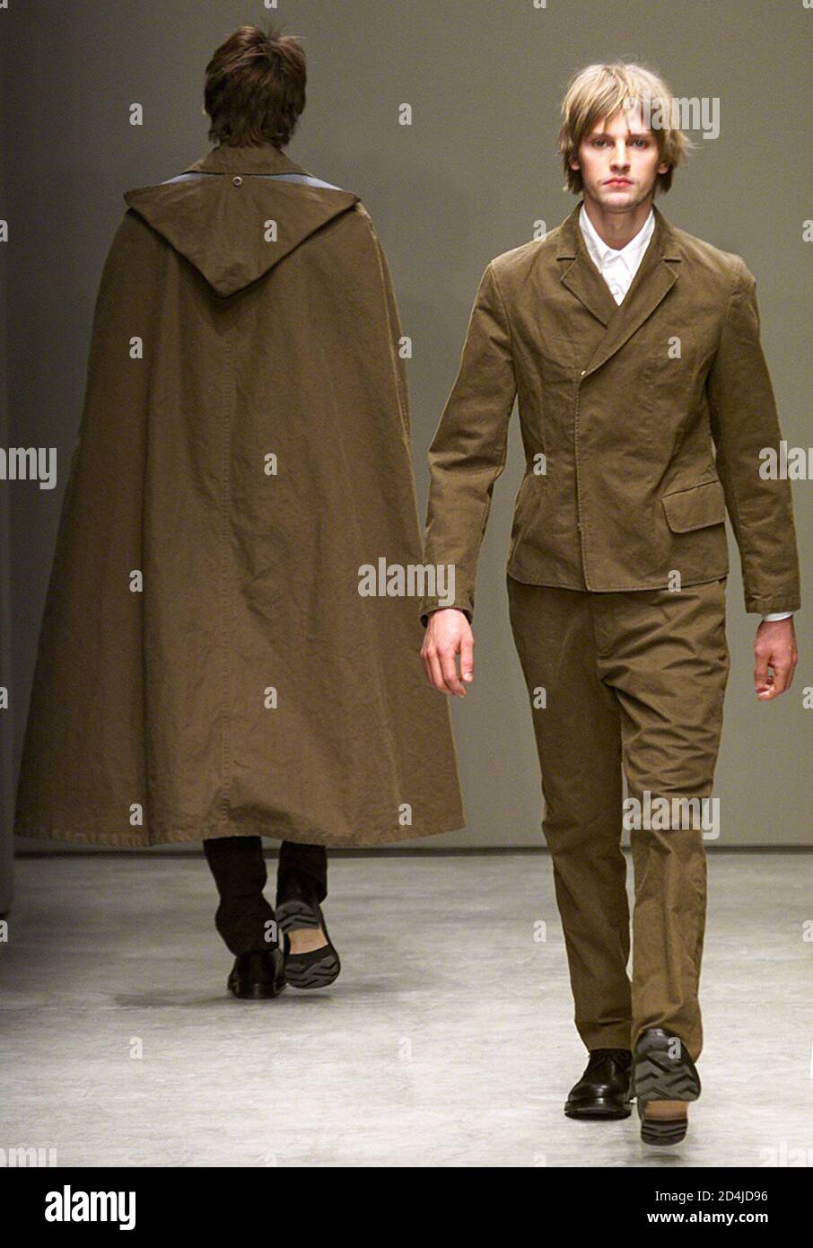 Two models wear a long cloak and a dressed as part of Miu-Miu Autumn/Winter  ready-to-wear men's collection 2001 in Milan January 14, 2001. The Milan  fashion show will run until January 18
