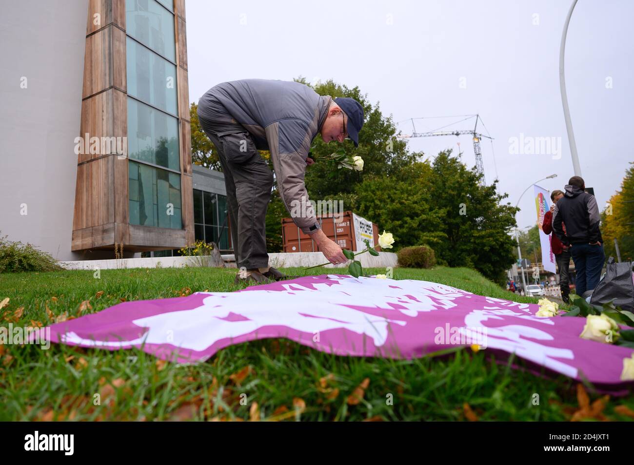 Chemnitz, Germany. 09th Oct, 2020. A participant in a vigil places white roses on a banner in front of the synagogue to commemorate the victims of the right-wing terrorist attack in Halle. On 9 October 2019 a heavily armed right-wing extremist had tried to storm the synagogue and cause a massacre among 52 visitors. When he failed to do so, he shot a passer-by and in a kebab bite a young man. Credit: Sebastian Kahnert/dpa-Zentralbild/dpa/Alamy Live News Stock Photo