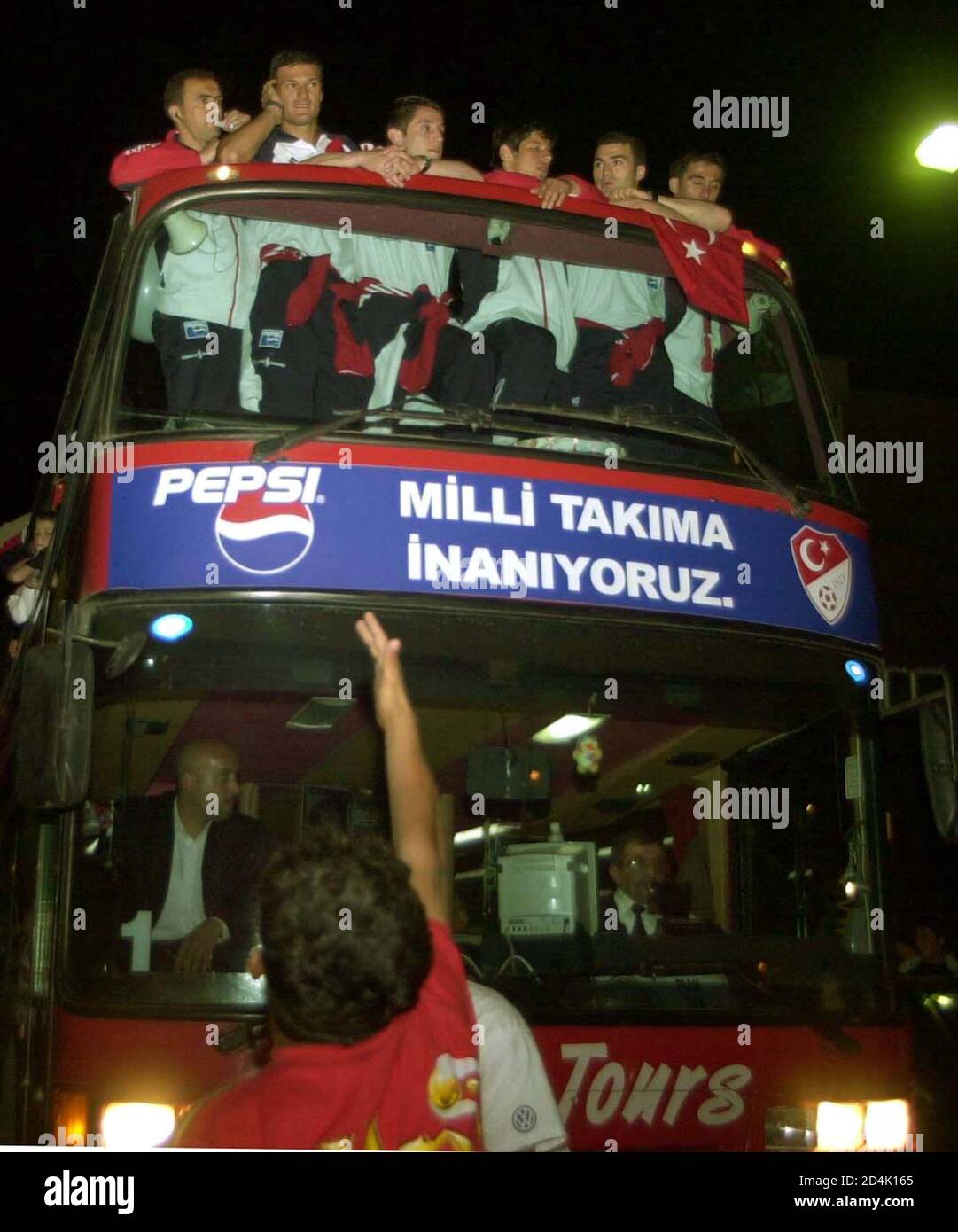 A Supporter Gestures To The Players Standing Atop A Bus In Istanbul Airport During A Farewell Ceremony For The National Soccer Team Heading To The World Cup Finals Late May 17 2002