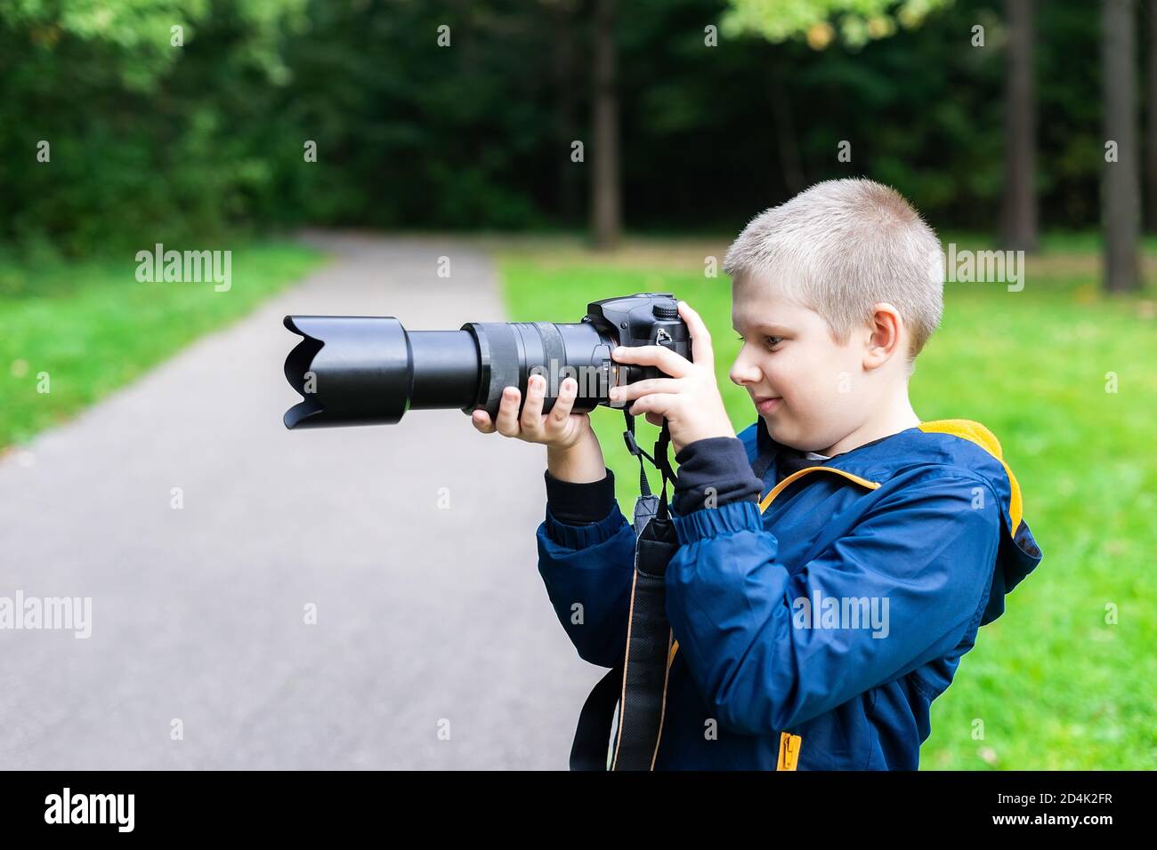 Young caucasian boy taking a shoot with his DSLR camera. Nature ambient