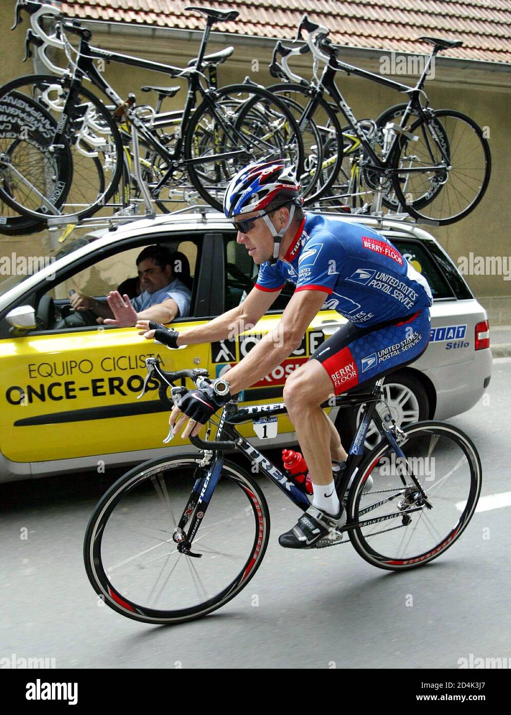 Four-time Tour winner US Postal team rider Lance Armstrong of the USA waves  to Once team Director Manuel Saiz as he rides past during the 204.5 second  stage of the Tour de