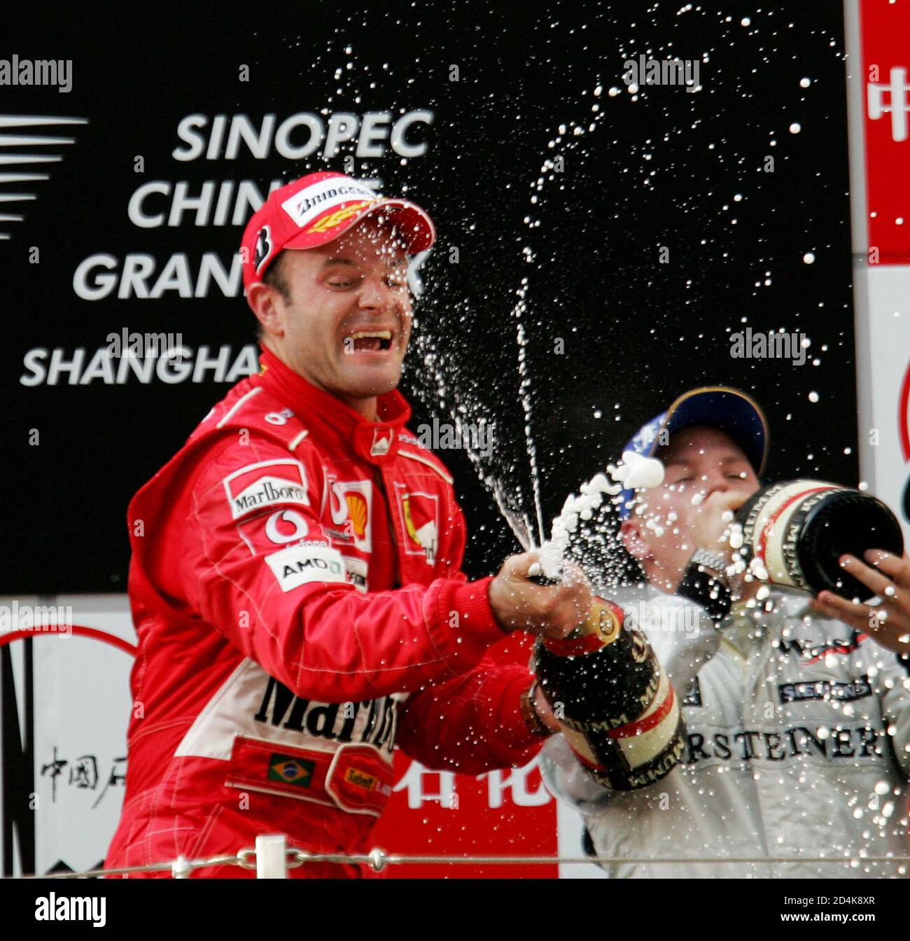 Brazilian Rubens Barrichello of Ferrari (L) and Finland's Kimi Raikkonen of  McLaren sprays champagne on the podium during the Chinese Grand Prix at  Shanghai Circuit September 26, 2004. Brazilian Rubens Barrichello won