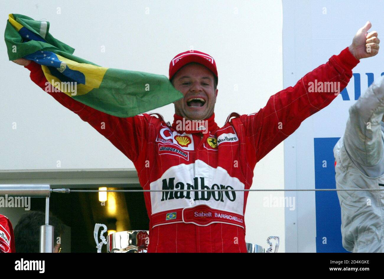 Brazilian Formula One driver Rubens Barrichello of team Ferrari holds up a Brazilian flag as he celebrates after the European Grand Prix at the Nuerburgring June 23, 2002. [Barrichello won the race followed by his team mate Michael Schumacher who placed second and Kimi Raikkonen of team McLaren Mercedes who placed third.] Stock Photo