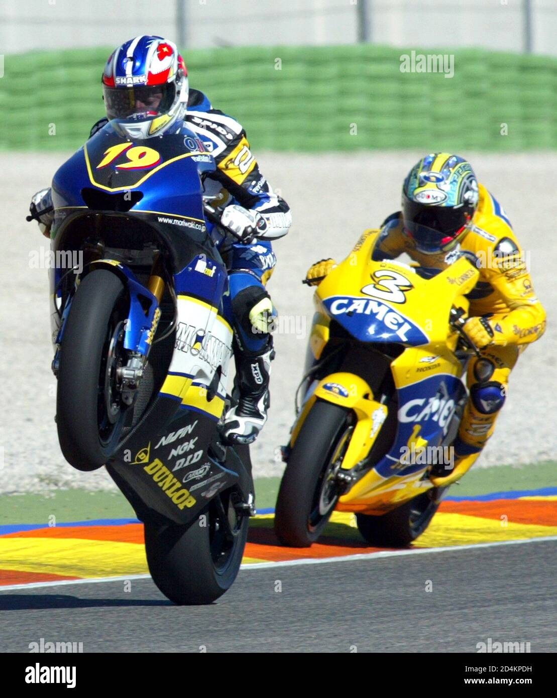 French Moto GP rider Olivier Jacque performs a wheel stand followed by  Italian Max Biaggi during qualifying practice at Valencia Motorcycle Grand  Prix. French Moto GP rider Olivier Jacque performs a wheel