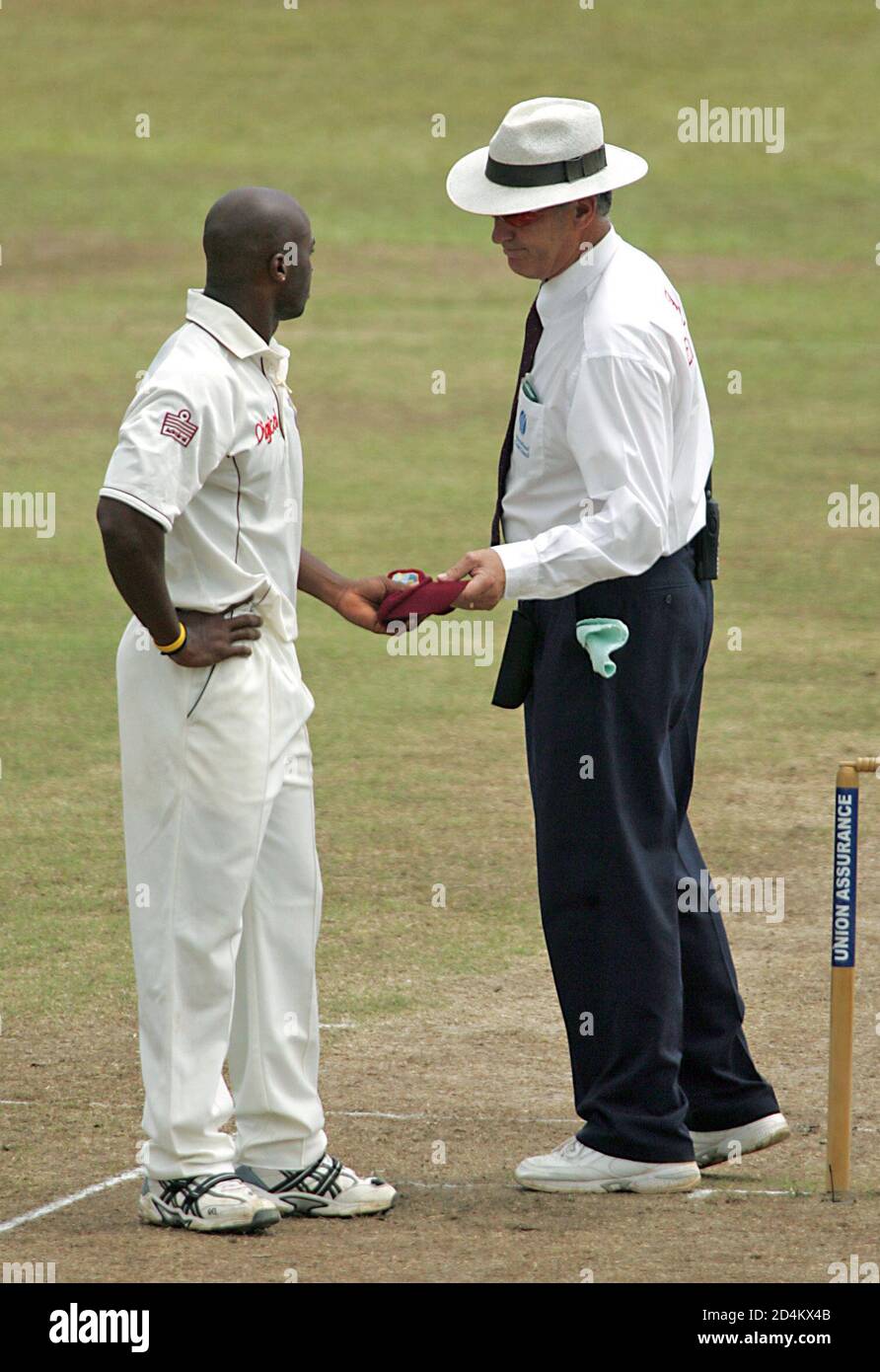 New Zealand umpire Hill hands West Indian fast bowler Best his cap after removing him from bowling during the fourth day of the second test cricket match against Sri Lanka in Kandy.  New Zealand umpire Tony Hill (R) hands West Indian fast bowler Tino Best his cap after removing him from bowling in rest of the match after the bowler bowled a second beamer against Sri Lankan batsman Rangana Herath (not in picture) during their fourth day of the second test cricket match at Asgiriya cricket stadium in Kandy, Sri Lanka July 25, 2005. REUTERS/Anuruddha Lokuhapuarachchi Stock Photo