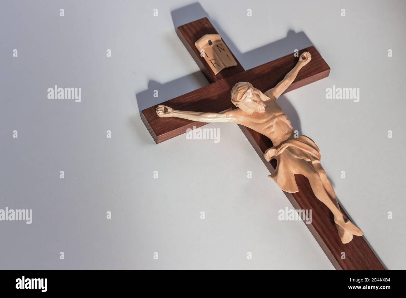 Catholic wood crucifix cross on plain white background in warm light Stock Photo