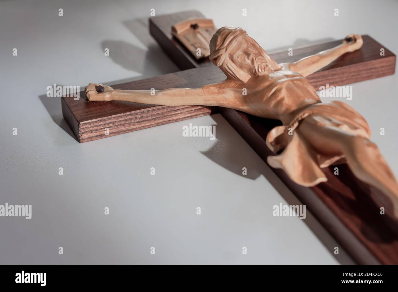 Catholic wood crucifix cross on plain white background in warm light Stock Photo