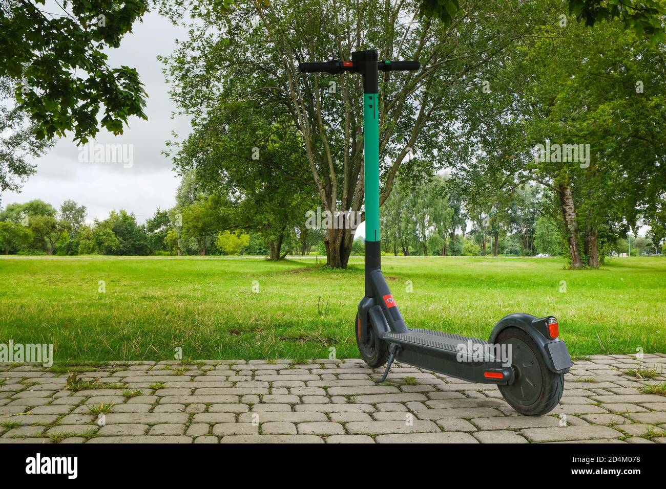 Electric scooter parked for hire on nature background, everyday transport for eco-friendly smart cities, ready for rent and online booking on app Stock Photo