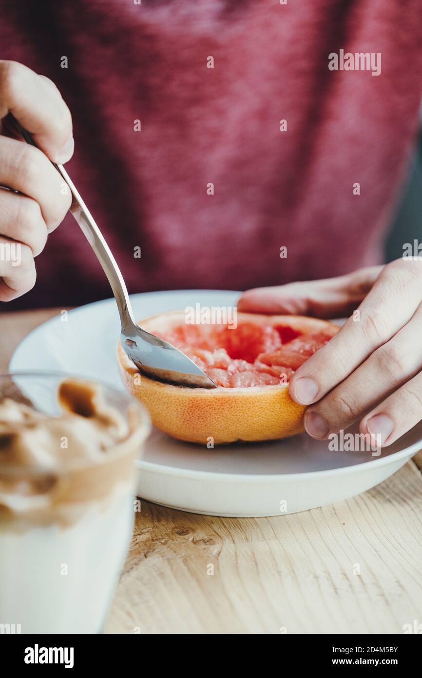Close up of hands with a grapefruit in a white plate Stock Photo