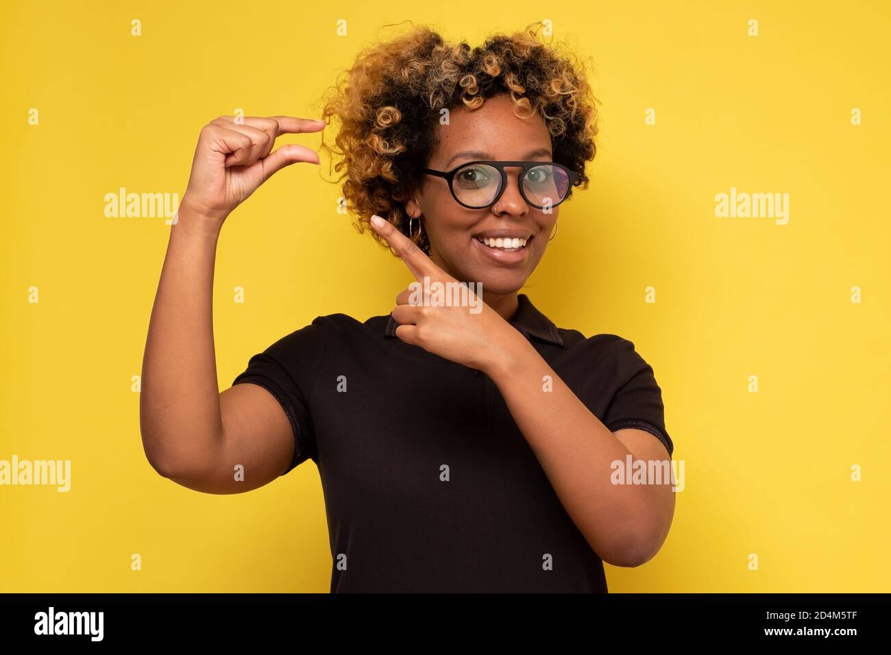 Glad beautiful african woman shows something small with hands Stock Photo